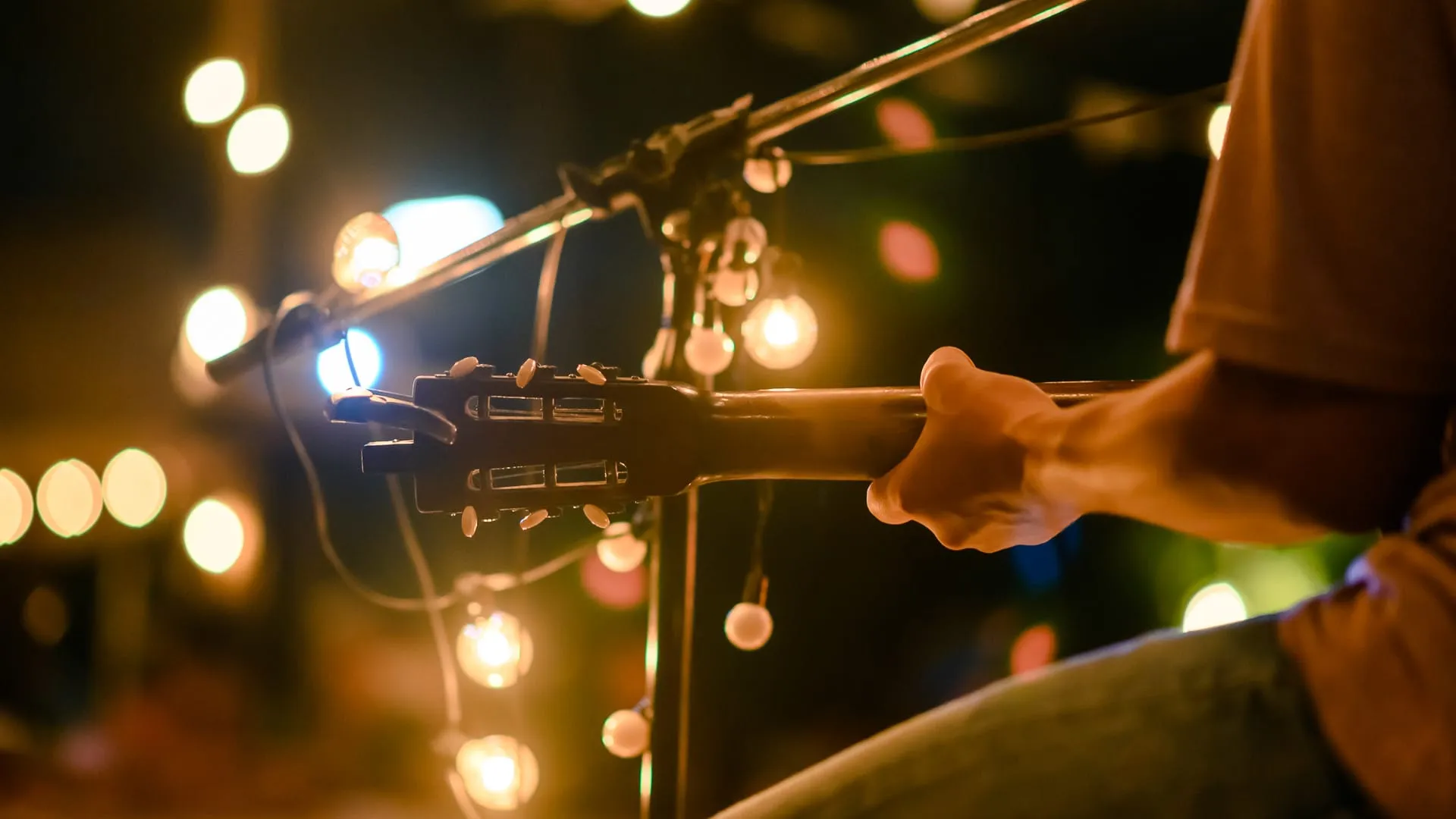 a guitarist singing, performing for other people on stage.