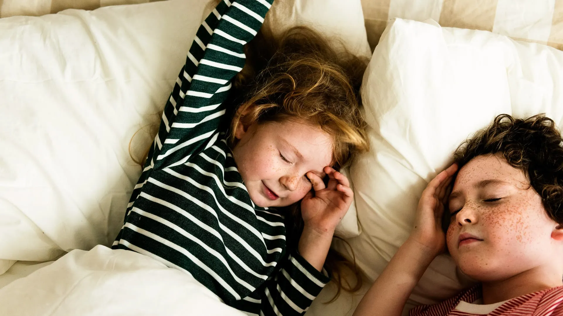 Kids sleeping in a bed.