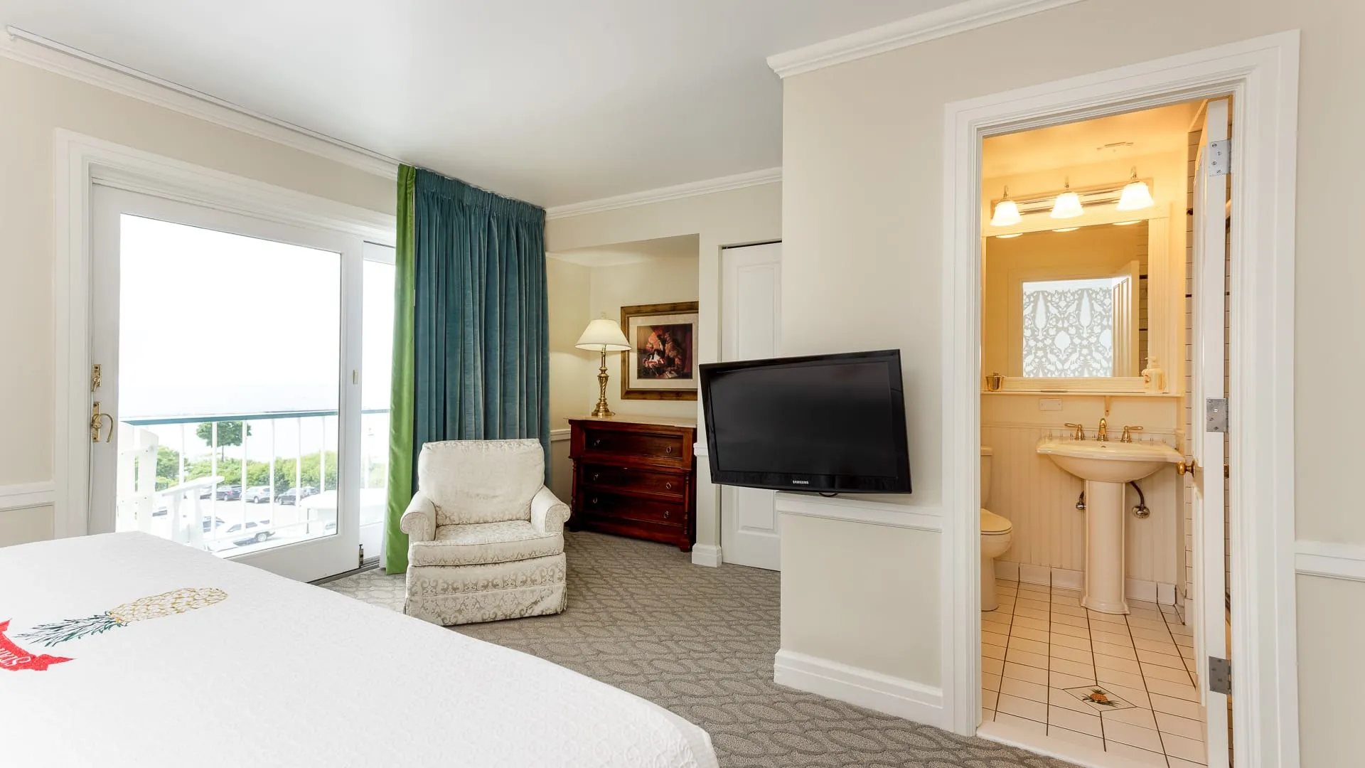 A hotel bedroom with bathroom, chair, and bed.