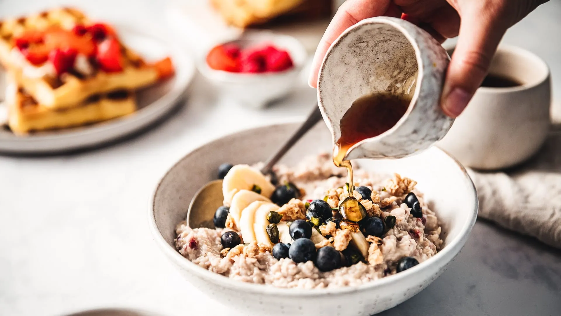 Honey being poured over oatmeal with fruit.