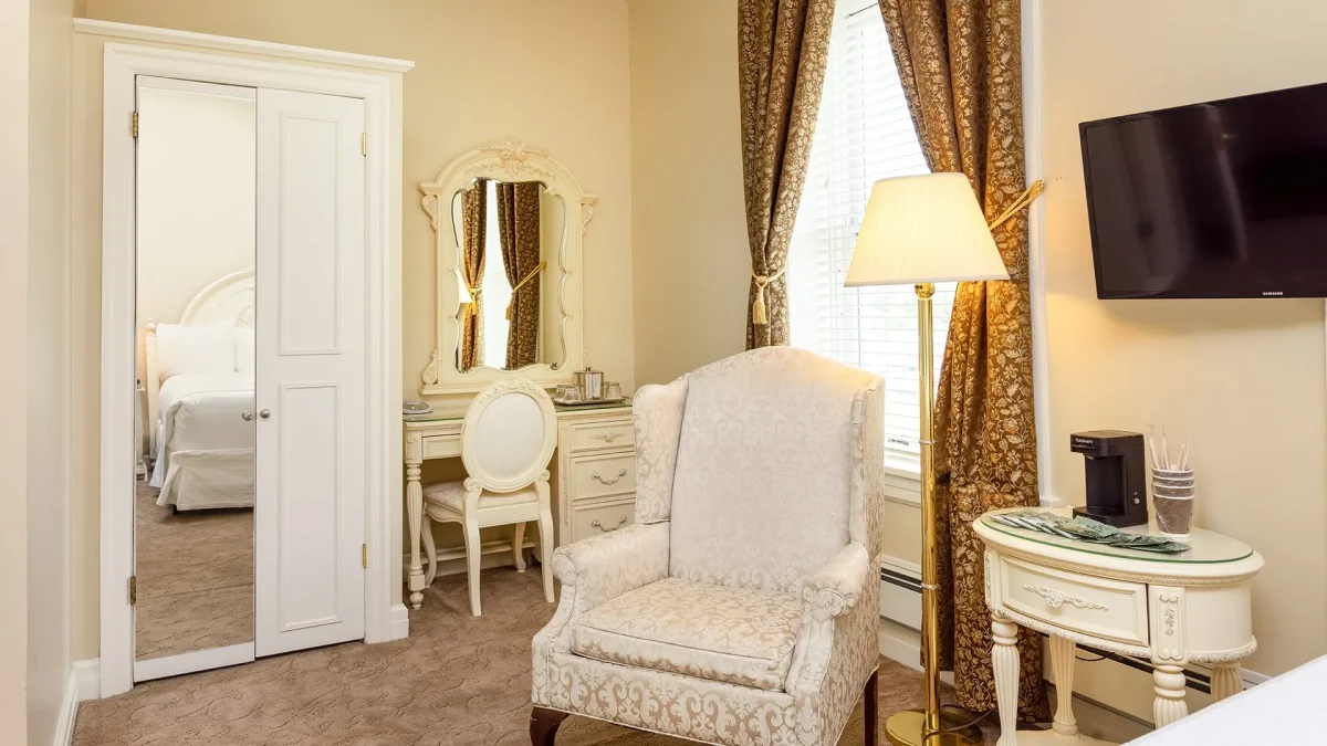 Hotel bedroom with brown carpet with tan wall with chair.
