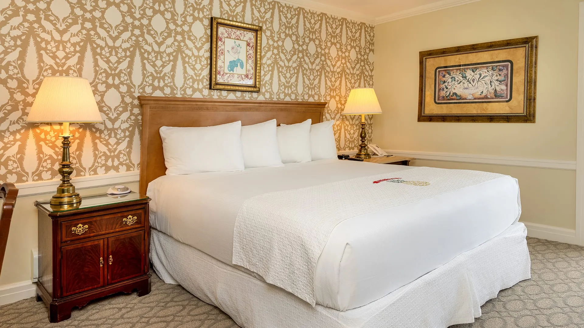 Hotel bedroom with gray carpet with large bed.