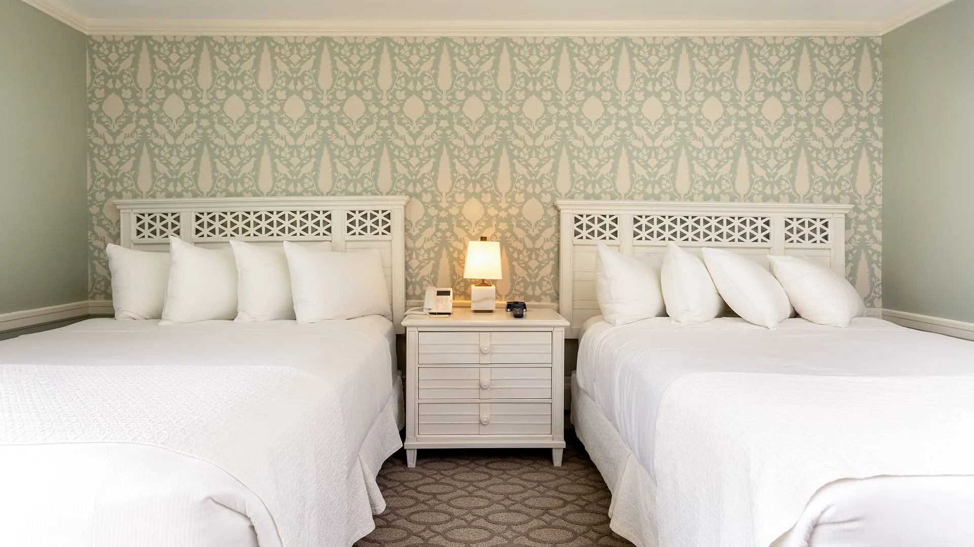 Hotel bedroom with gray carpet with twin bed with green painting.