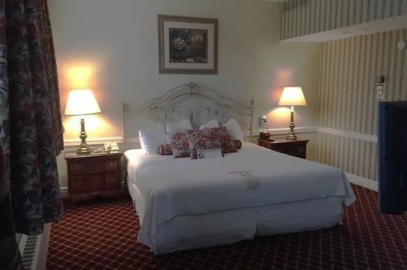 Hotel bedroom. Darkly lit large bed with gift on bed.