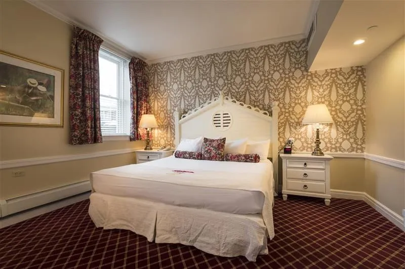 Hotel bedroom with red carpet with large bed.