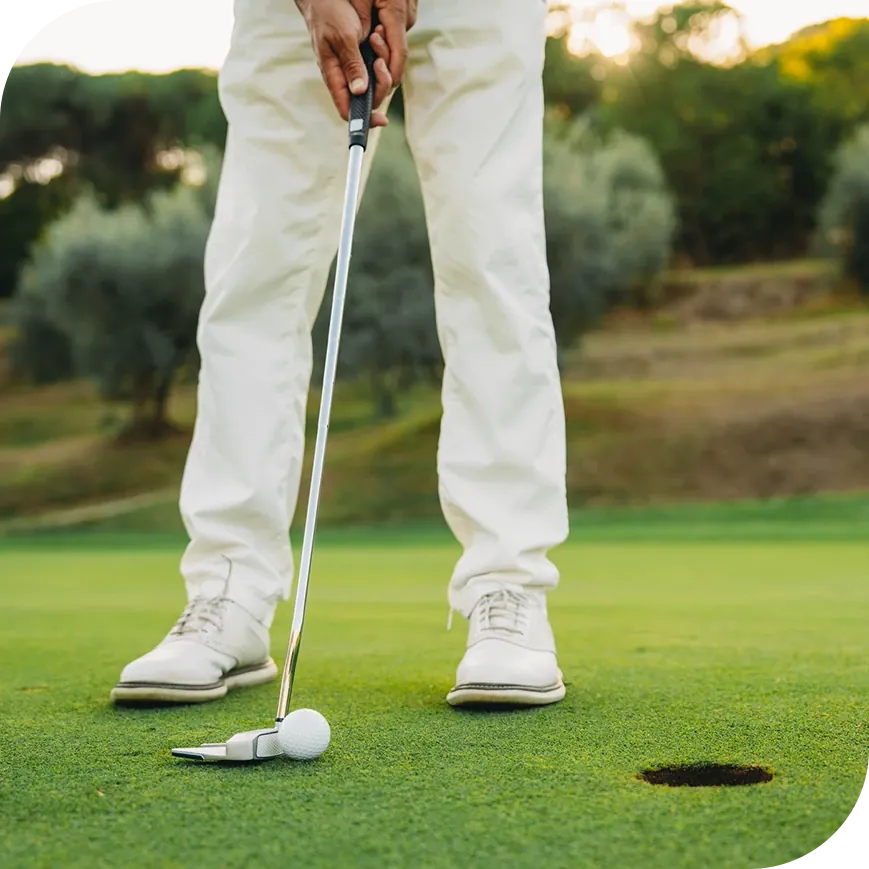 A man hitting a golf ball into a hole.