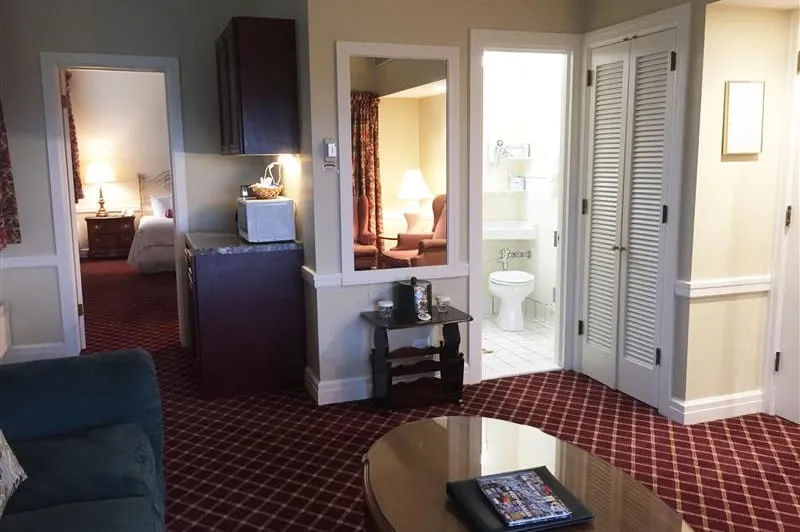 Hotel bedroom with red carpet with view of bathroom and living room.