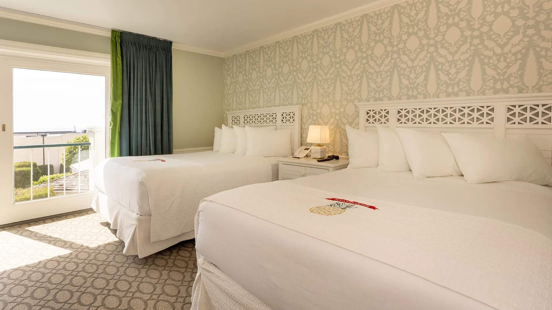 View of hotel bedroom with twin bed and balcony.