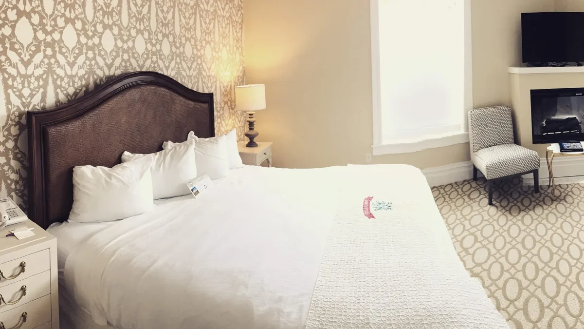 Hotel bedroom with white carpet with large bed.